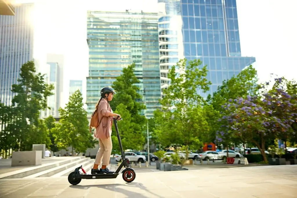 Full length side view of environmentally aware professional in work attire, safety helmet and backpack, beginning her commute home.